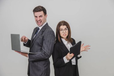 Başarılı iş ortakları omuz omuza verileri kontrol ediyor. Adam dizüstü bilgisayarla çalışıyor, tedirgin bir yüz ifadesi, tabletli bir kadın, dişlerini düzeltiyor..