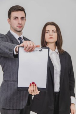 Bulanık başarılı iş çifti kendine güvenen yüz ifadeleri ile ayakta duruyor, kameraya uzanan boş kağıt için boş bir pano.