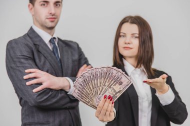Bulanık zengin, kendine güvenen iş çifti. Adam elleri bağlı ayakta duruyor. Onun tarafındaki kadın bir dolar banknot hayranı..