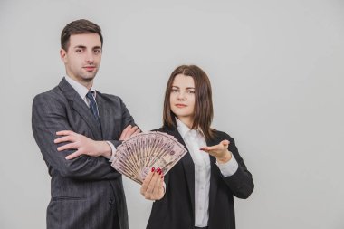 Zengin, kendine güvenen bir çift. Adam elleri bağlı ayakta duruyor. Onun tarafındaki kadın bir dolar banknot hayranı..