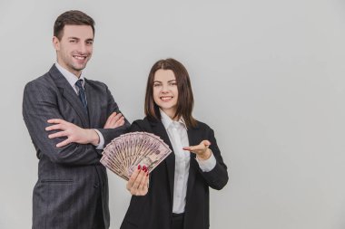 Güler yüzlü, kendine güvenen iş çifti. Adam elleri bağlı ayakta duruyor. Onun tarafındaki kadın bir dolar banknot hayranı..