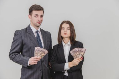 Mutlu iş çifti ayakta duruyor, ellerinde dolar banknotları tutuyorlar, kendilerine güveniyorlar..