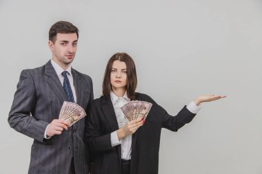 Kadın ve erkek ellerinde banknot hayranıyla ayakta duruyor. Kadın kendi tarafındaki boşluğu işaret ediyor..