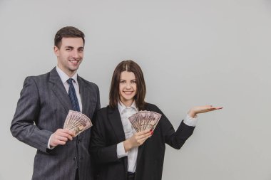Kadın ve erkek ellerinde banknot hayranıyla ayakta duruyor. Kadın kendi tarafındaki boşluğu işaret ediyor..