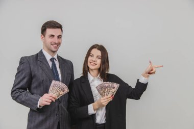 Kadın ve erkek ellerinde banknot hayranıyla ayakta duruyor. Kadın parmağını yan tarafındaki boşluğu işaret ediyor..