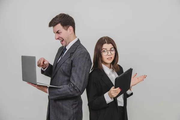 Busy successful work partners standing shoulder to shoulder, checking data. Man working with laptop, looking with irritated face expression, woman with tablet, woman asking for silence . — Stock Photo, Image