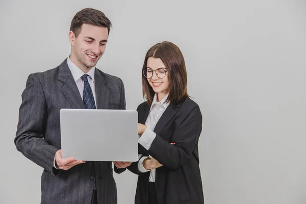 Partnerzy biznesowi stoją, sprawdzają dane w laptopie. Kobieta wskazuje palcem na coś w laptopie, więc jej partner zwraca uwagę. — Zdjęcie stockowe