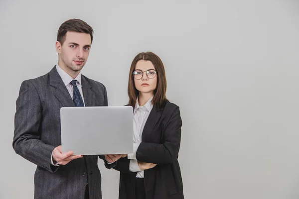 Socios de negocios de pie, comprobando los datos en el portátil. La mujer está de pie, con las manos cruzadas. Expresiones faciales confiables . — Foto de Stock