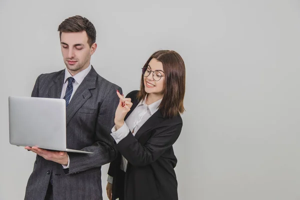 Handsome man standing, working with laptop. Woman is pointing from mans behind at something in the laptop, interfering him. Man is annoyed because of this. — Stock Photo, Image