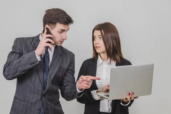 Бизнесмен держит ноутбук, проверяет данные. Мужчина на ее стороне говорит по телефону, указывая пальцем на что-то в ноутбуке . — стоковое фото