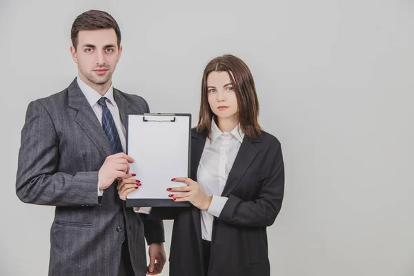 Couple d'affaires réussi debout avec des expressions faciales confiantes, tenant ensemble un presse-papiers avec feuille de papier claire vide pour le texte . — Photo