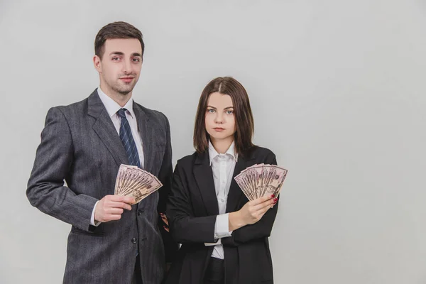 Felice coppia d'affari in piedi, tenendo i fan di banconote in dollari nelle loro mani, guardando sicuro di sé . — Foto Stock