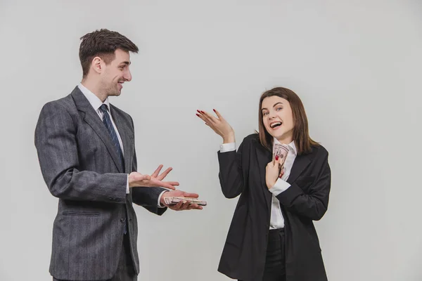 Affärspartners står upp och delar på pengar. Människan är förvirrad. Kvinnan tittar slarvigt, håller hand med sedlar nära bröstet. — Stockfoto