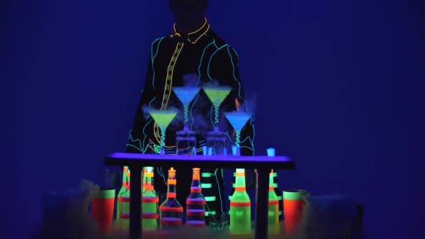 Бармен жонглирует. Коктейльные бокалы полны напитков и сухого льда на баре. Потрясающее шоу. Разноцветные огни привели. Медленное движение. 4K . — стоковое видео
