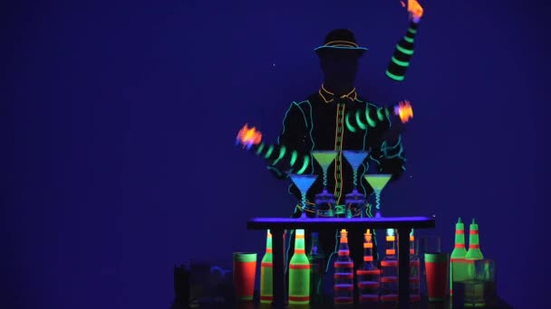 Barman is juggling burning bottles. Cocktail glasses are full of beverage and dry ice on bar. Fabulous show. Colorful lights led. Slow motion. 4K. — ストック動画