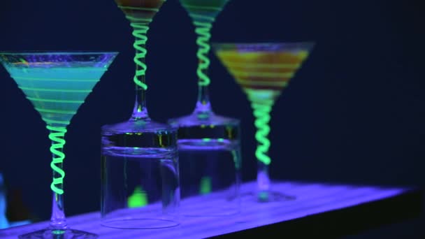Close up cocktail glasses, which are full of beverage and dry ice on bar. Barman is pouring alcohol into glasses. Fabulous show. Colorful lights led. Slow motion. 4K. — 비디오