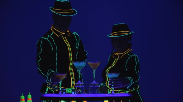 Show de Barmen. Actuación. Barmaid y barman ofrecen deliciosos cócteles, sobre fondo azul brillante. En cámara lenta. 4K . — Vídeo de stock