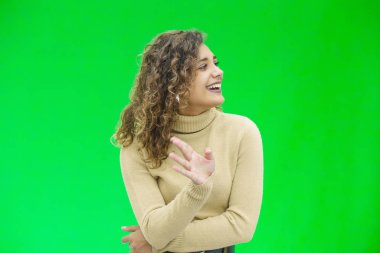 Herkese merhaba. Kendine güvenen çekici ve kendine güvenen bir kadının portresi merhaba diyor, yeşil arka planda güler yüzlü..