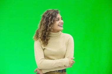Herkese merhaba. Kendine güvenen çekici ve kendine güvenen bir kadının portresi yana bakıyor, yeşil arka planda dostça gülümsüyor..