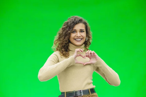 Gyönyörű fiatal nő zöld háttér csinál szív alakú kezével. — Stock Fotó