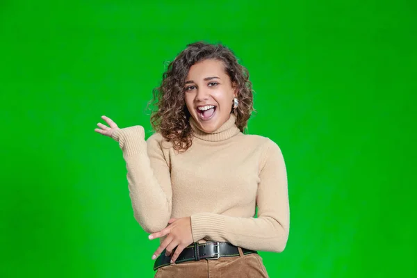 Hola a todos. Retrato de mujer atractiva y segura de sí misma saludando con la mano, sonriendo amigable sobre fondo verde . —  Fotos de Stock