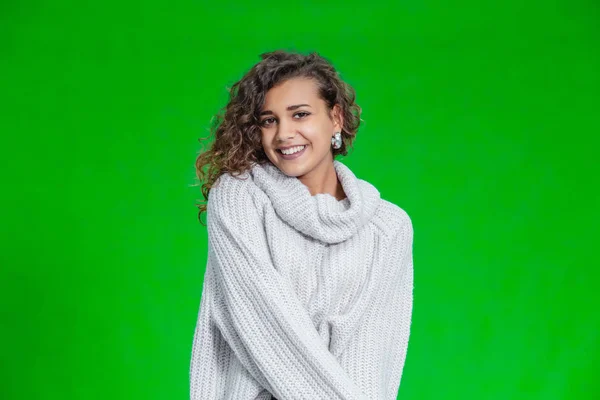 Gyönyörű természetes fiatal mosolygós lány visel kötött pulóver és pózol a zöld háttér. — Stock Fotó