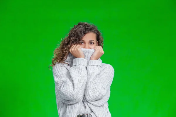 Hermosa joven sonriente natural con suéter de punto y posando sobre fondo verde . —  Fotos de Stock