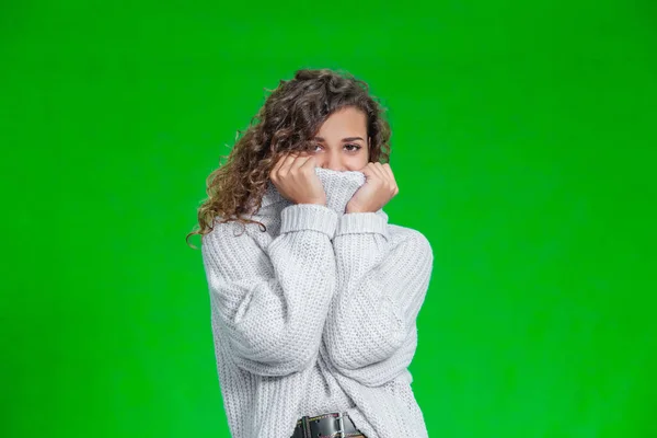Beautiful young lady in warm knitted handmade clothes standing aginst bright green background. — 스톡 사진