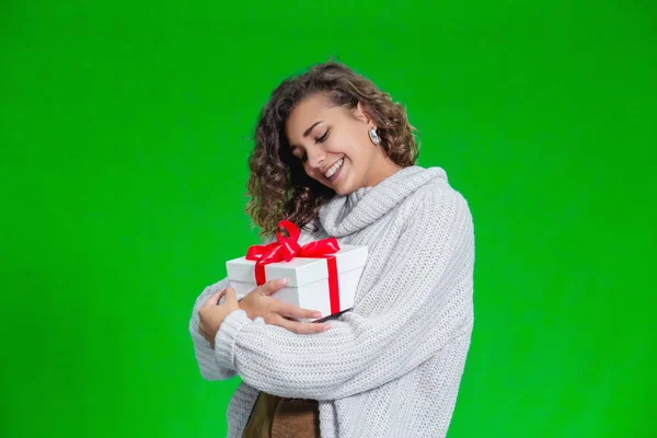 Jul kvinna som håller julklappar i armarna bär varm ull tröja isolerad på grön bakgrund. — Stockfoto