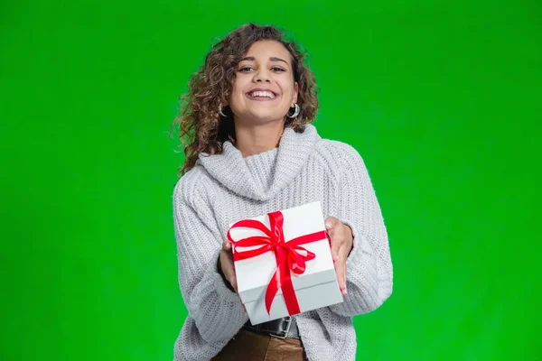 Boże Narodzenie kobieta trzyma prezenty w ramionach w ciepłym wełnianym swetrze izolowane na zielonym tle. — Zdjęcie stockowe