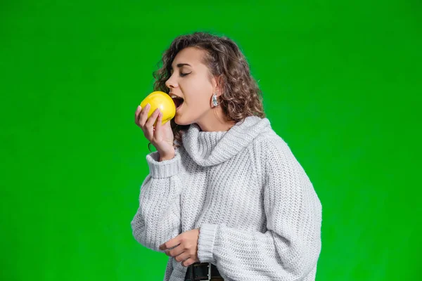 Concepto de alimentos orgánicos. Mujer sonriente mirando una manzana amarilla con la tentación y el deseo de morderla . — Foto de Stock