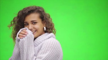 Çekici Afro-Amerikalı kız geniş bir kesime gülümsüyor. O, beyaz kazak giyerek parmaklarını ısıtıyor. Kapatın. Boşluğu kopyala.