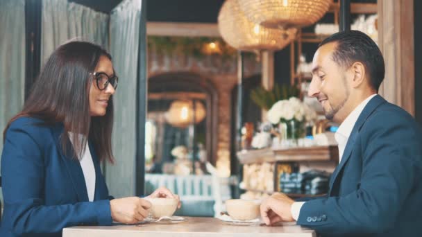 Twee zakenmensen lunchen samen. De vrouw en de man in een restaurant of een koffieshop roeren en drinken koffie. Kopieerruimte. — Stockvideo