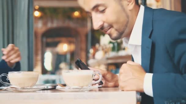 Twee zakenmensen lunchen samen. De man in een restaurant of koffieshop drinkt koffie. Kopieerruimte. — Stockvideo