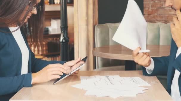 Koyu mavi takım elbiseli iki iş adamı çalışıyor. Kadın tablet üzerinde çalışıyor, kahvecide oturuyor. Adam önemli evraklara bakıyor. Ekin. Kapatın. Boşluğu kopyala. — Stok video