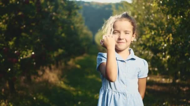 La petite fille offre une pomme rouge à l'extérieur. Elle fait un geste du pouce. Ferme là. Espace de copie. 4K . — Video