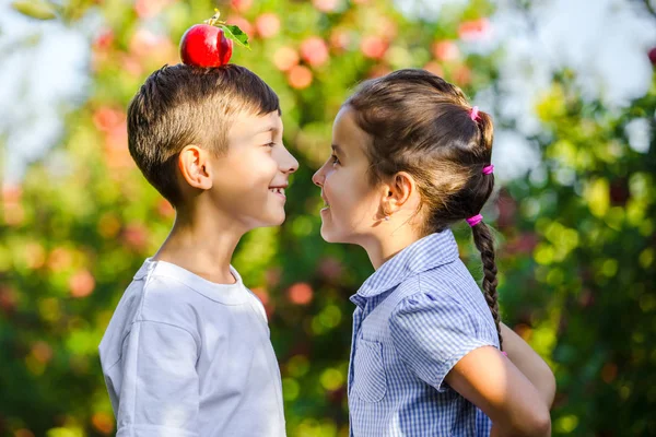 Мальчик с яблоком на голове пытается сохранить равновесие, в то время как ее красивая сестра смотрит на него улыбаясь . — стоковое фото