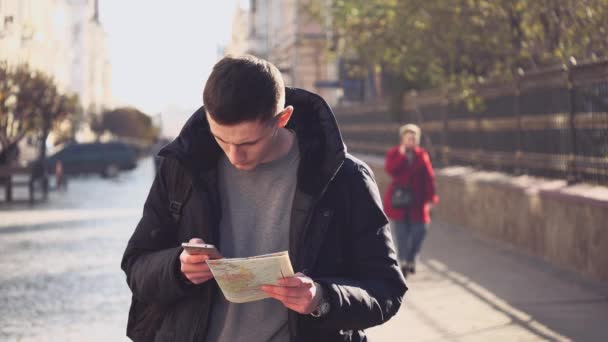 Handsome guy is strolling and learning the map, holding a phone in his hand. Lost in foreign city. He is going out of focus. Action. Animation. 4K. — 비디오