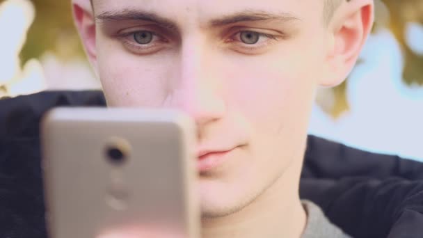 Közelről. Jóképű fiatalember mobilt használ a városban. Felvétel. Animáció. 4k. — Stock videók