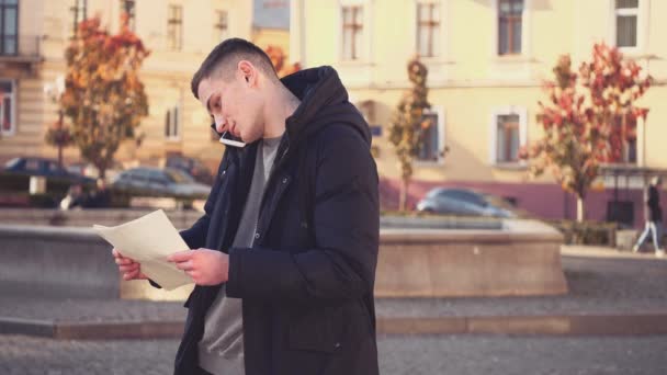 Handsome guy lost in foreign city. Confused facial expression. Tourist is asking for help, talking on the phone. Copy space. Action. Animation. 4K. — Stok video