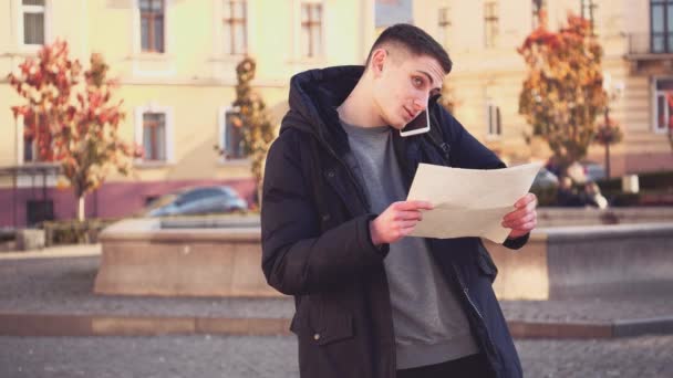 Snygg kille vilse i en främmande stad. Förvirrad ansiktsuttryck. Turisten ber om hjälp och pratar i telefon. Uppfattat utrymme. Börja. Animering. 4k. — Stockvideo