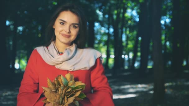 Slowmo. Lovely girl is holding a bunch of autumn leaves. Blurred background. Close up. Copy space. 4K. — 비디오