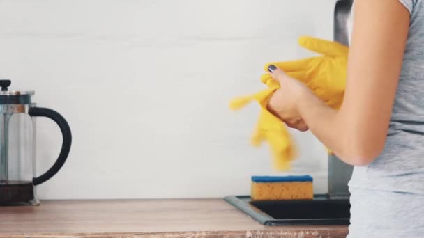 Жінка відкладає жовті гумові рукавички біля кухонної мийки та сучасного чайника. Врожай. Близько. 4-кілометровий . — стокове відео