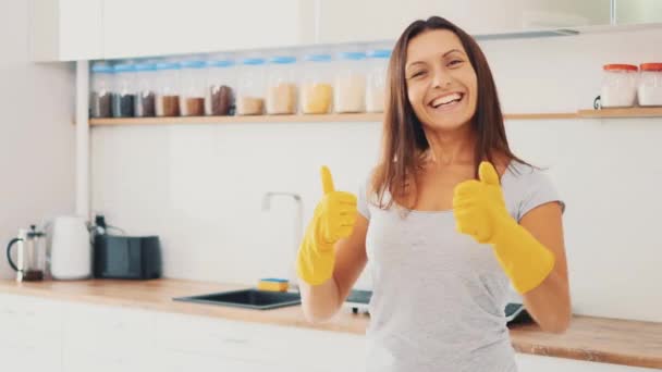 Жінка одягає жовті гумові рукавички. Вона показує свої великі пальці і широко посміхається. Близько. 4-кілометровий . — стокове відео