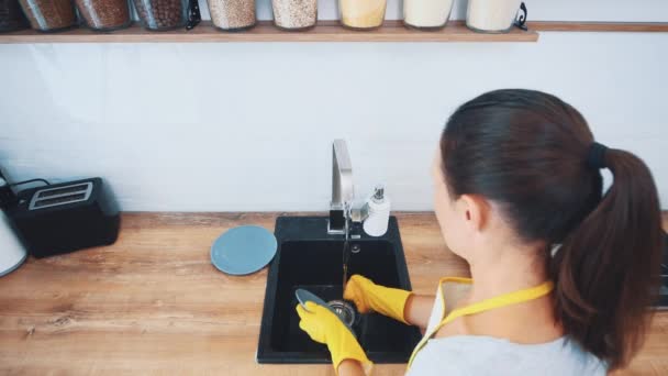 Woman is washing dishes in a kitchen sink with a sponge. Close up. Top view. 4K. — Stock Video