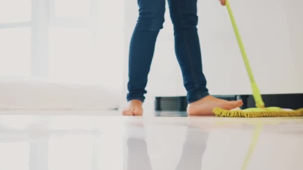 Woman is mopping the kitchen floor with a swab. Close-up legs. Copy space. 4K. — Stock Video