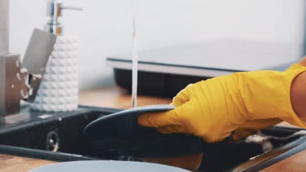 Las manos de las mujeres están lavando los platos en un fregadero de cocina con una esponja. De cerca. 4K . — Vídeos de Stock