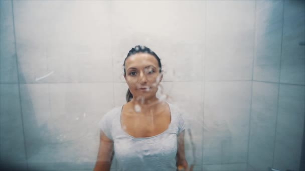 A nő ablakot mos a fürdőszobában. Szappanos vizet fröcsköl az üvegre. Megtisztítja az üveget a piszoktól. Közelről. 4k. — Stock videók
