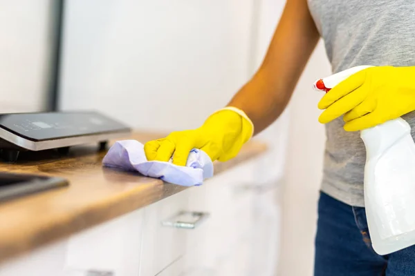 Przycięte ujęcie kobiecych dłoni wycierających powierzchnię blatu, używając szmaty i detergentu. — Zdjęcie stockowe