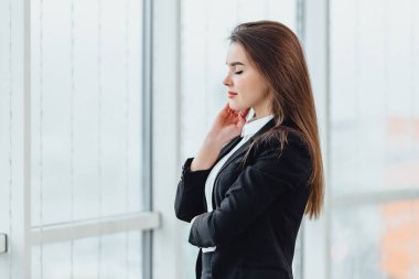 Neşeli kadın pencereden bakıyor, yeni ofisinde hoş duygular ve kendine güvenini ifade ediyor..